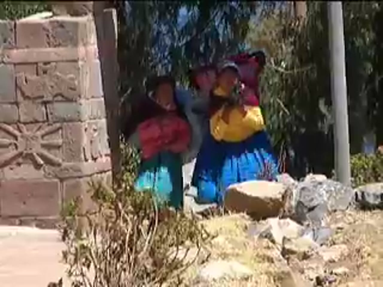 Mujeres de Amantaní junto a un arco de piedra